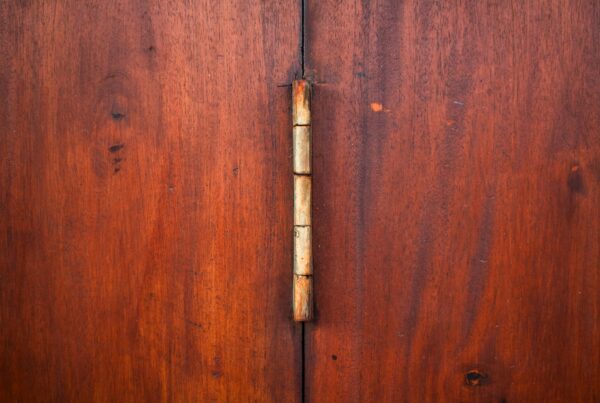 Close-up of a brass hinge on a wooden cabinet door, representing the connection points an AI agent manages between systems