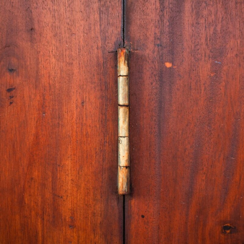 Close-up of a brass hinge on a wooden cabinet door, representing the connection points an AI agent manages between systems