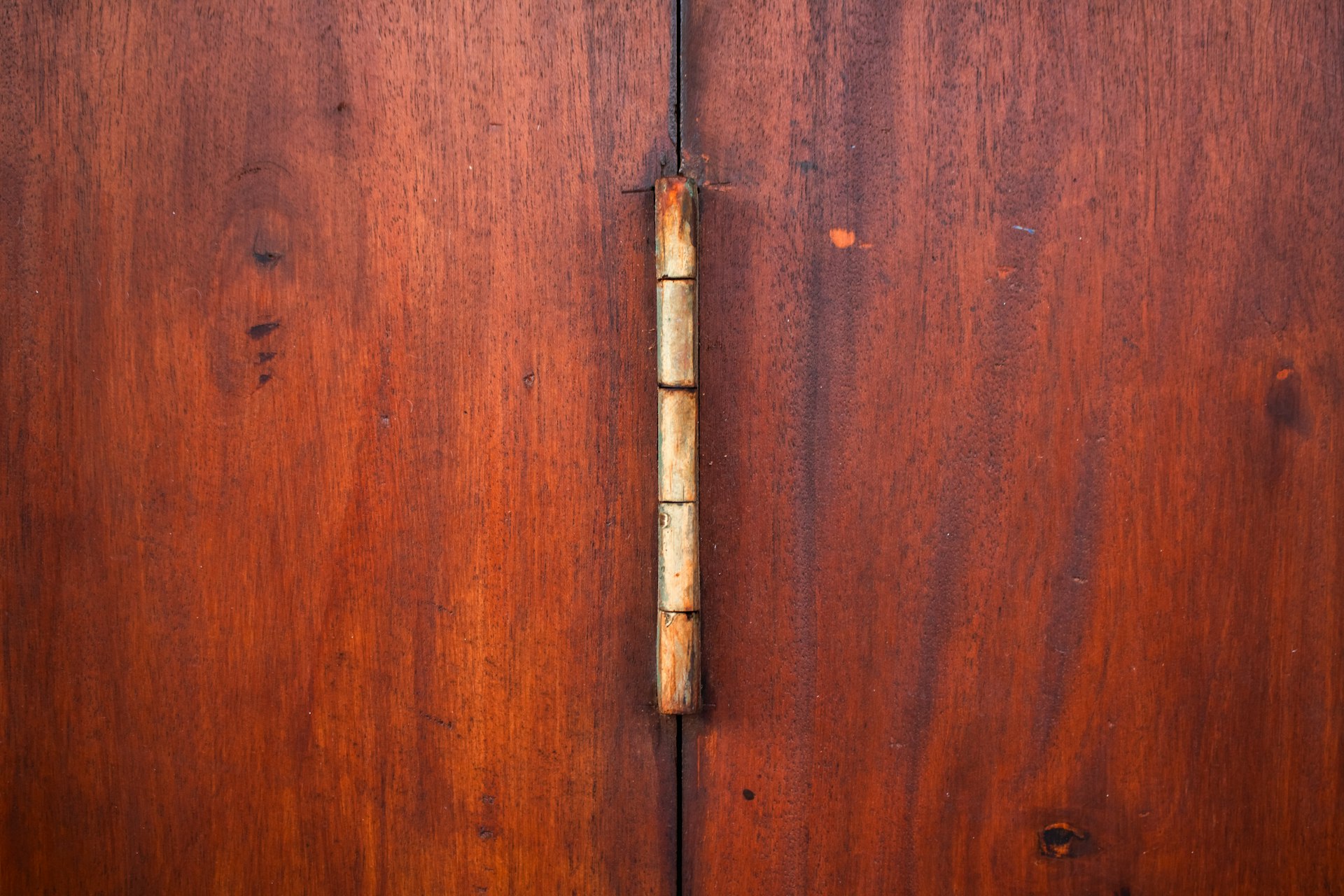 Close-up of a brass hinge on a wooden cabinet door, representing the connection points an AI agent manages between systems
