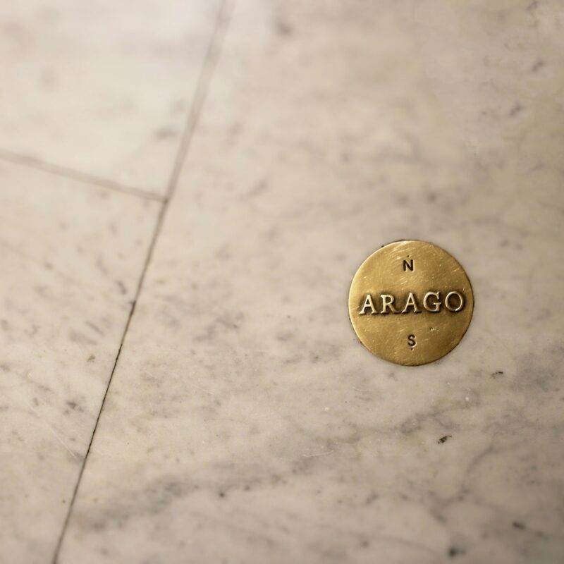 A brass balance scale resting on marble, representing weighing the true cost drivers of AI consulting in Canada