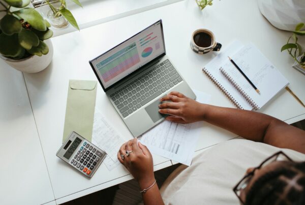 A desk with budget planning documents and a calculator, representing building next years AI budget from this years actual results