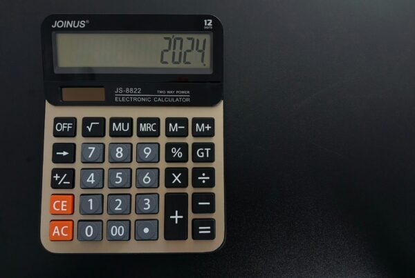 A vintage calculator on a dark desk, representing the fully loaded cost calculation behind a credible AI return on investment