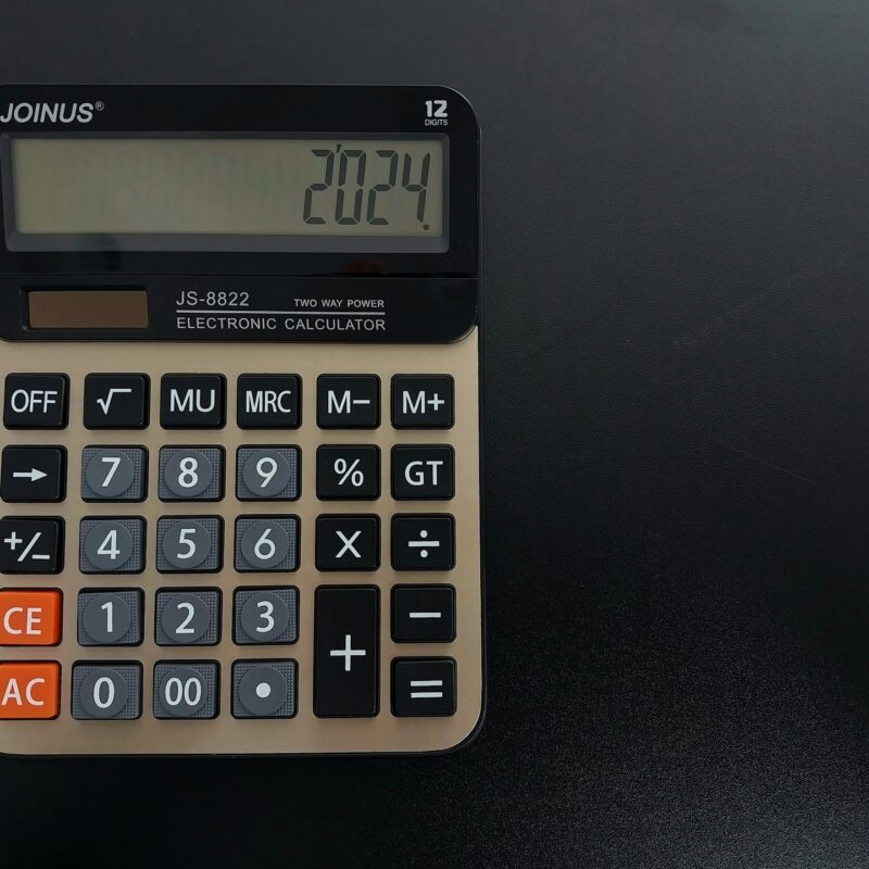 A vintage calculator on a dark desk, representing the fully loaded cost calculation behind a credible AI return on investment
