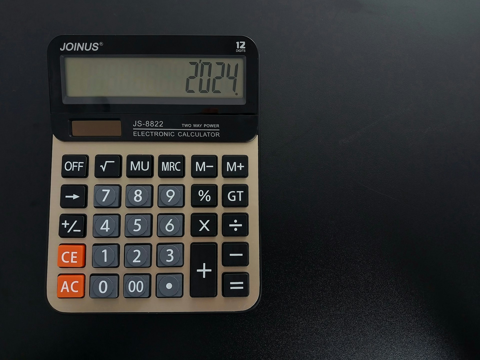 A vintage calculator on a dark desk, representing the fully loaded cost calculation behind a credible AI return on investment