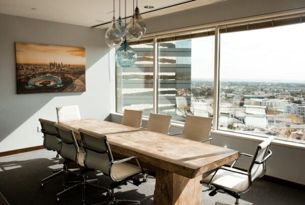 A polished wood boardroom table catching soft morning light, representing the working session where an executive AI workshop produces decisions