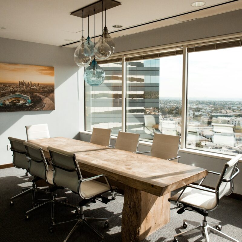 A polished wood boardroom table catching soft morning light, representing the working session where an executive AI workshop produces decisions