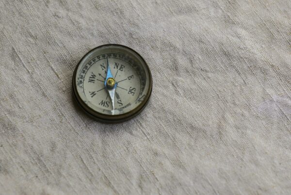 A brass drafting compass resting on paper, representing the precision of building a usable AI roadmap