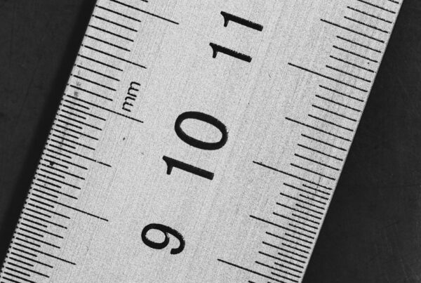 A brass measuring ruler on a dark desk, representing the signals that show whether an AI rollout is actually working