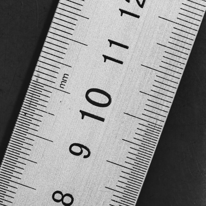 A brass measuring ruler on a dark desk, representing the signals that show whether an AI rollout is actually working
