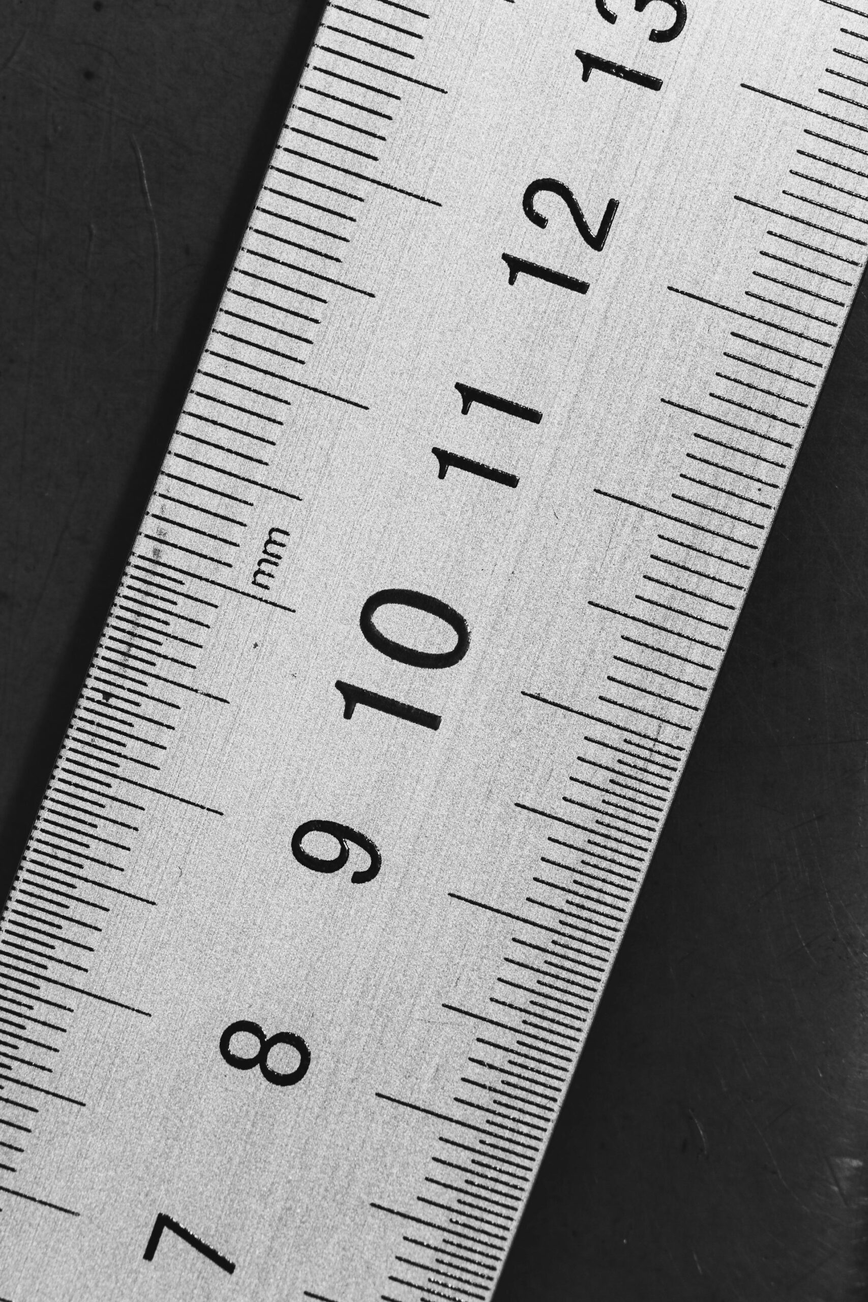 A brass measuring ruler on a dark desk, representing the signals that show whether an AI rollout is actually working