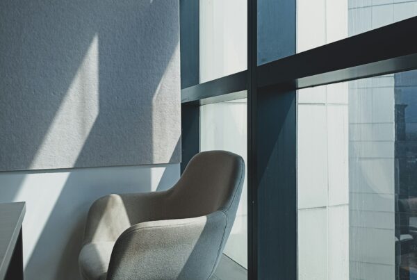 Empty office chairs in soft summer light, representing vacation coverage gaps that AI-assisted workflows can help close