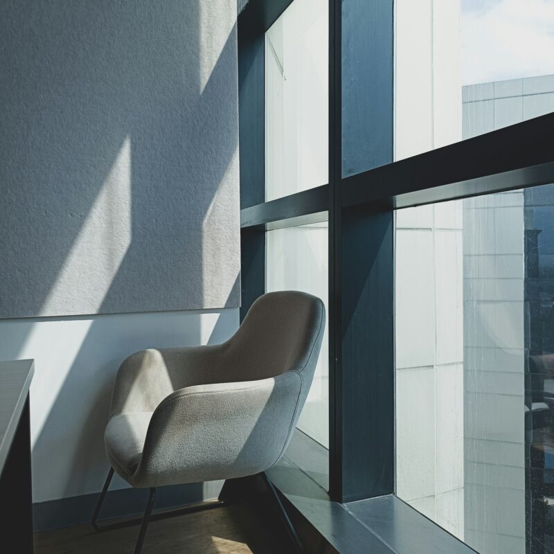 Empty office chairs in soft summer light, representing vacation coverage gaps that AI-assisted workflows can help close