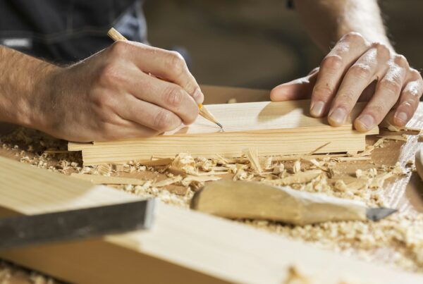 A partially completed dovetail joint in pale wood, representing an AI pilot left unfinished at the handover