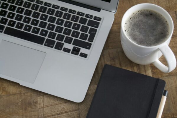 Laptop and coffee mug on a wooden table, a setting for reading an AI glossary for business