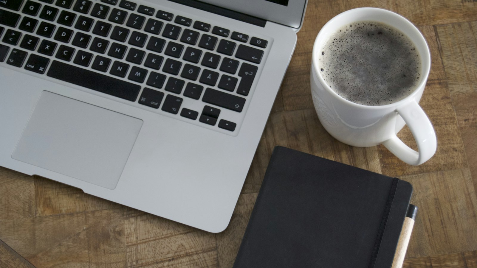Laptop and coffee mug on a wooden table, a setting for reading an AI glossary for business
