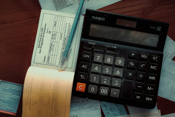 Calculator and receipts on a wooden table, illustrating AI total cost of ownership