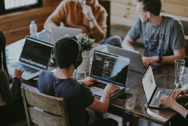 People working on laptops at a shared table, illustrating AI training in Alberta