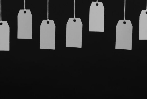 A row of blank price tags hanging on strings against a dark background