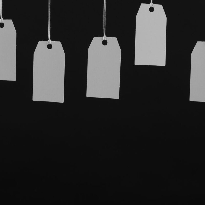 A row of blank price tags hanging on strings against a dark background
