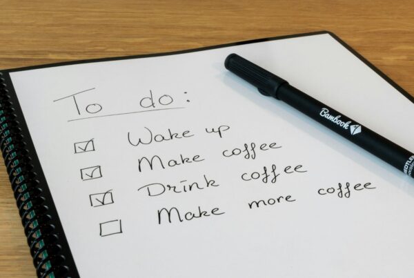 A handwritten checklist in a notebook with a pen