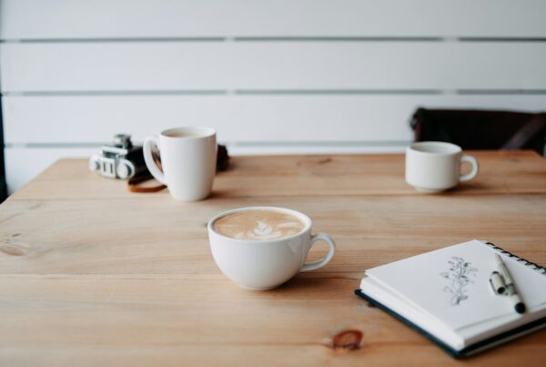 Two coffee cups and an open notebook on a table set for a meeting