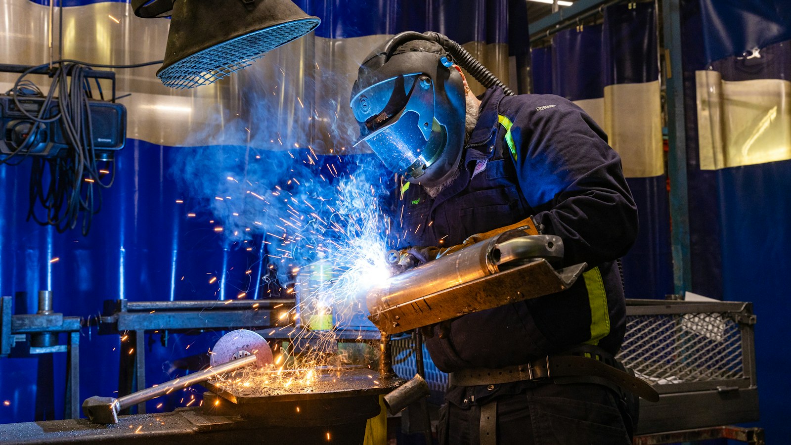 Welder cutting metal in a shop with sparks flying, illustrating custom AI vs off-the-shelf