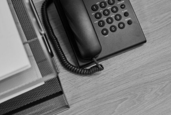 A desk telephone beside a tray stacked with printed sheets