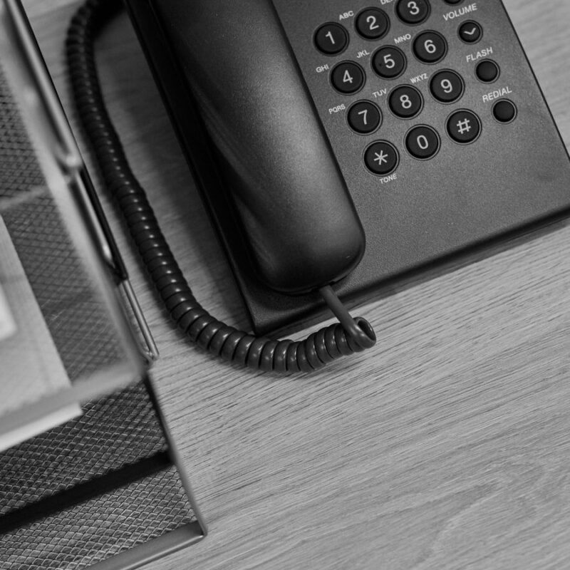 A desk telephone beside a tray stacked with printed sheets