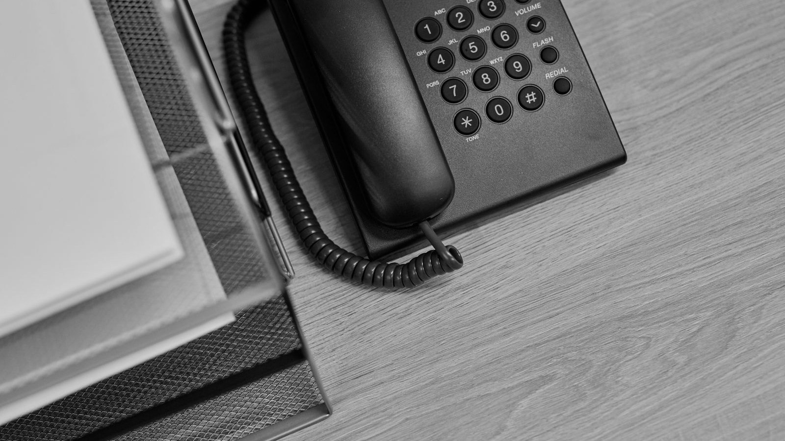 A desk telephone beside a tray stacked with printed sheets