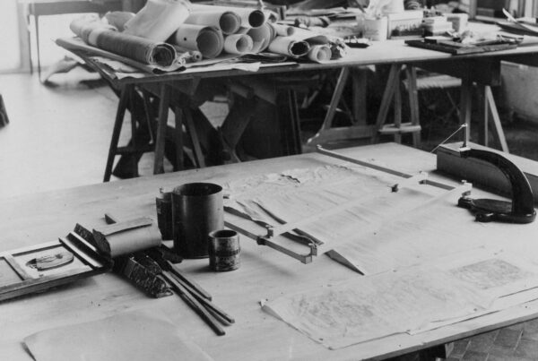 A drafting desk covered in technical drawings and tools