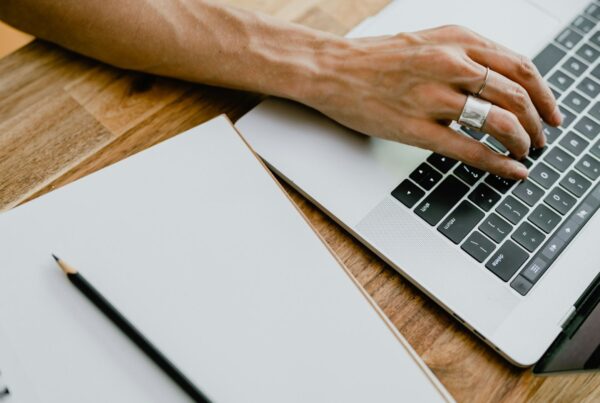 Hands typing on a laptop on a wooden desk