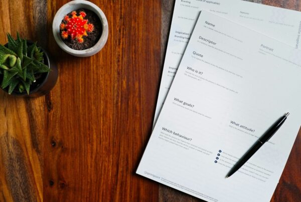 Printed paperwork and a pen on a wooden desk
