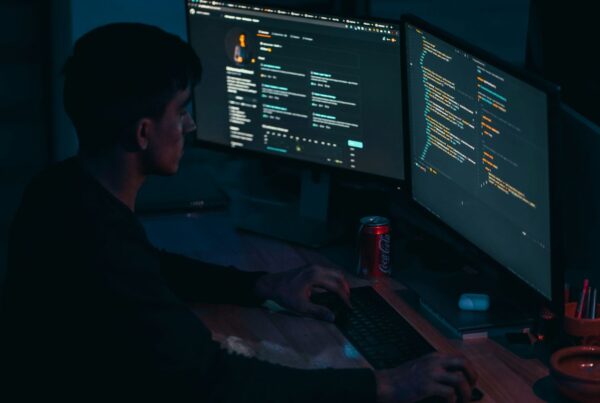 A person working at monitors in a dark office