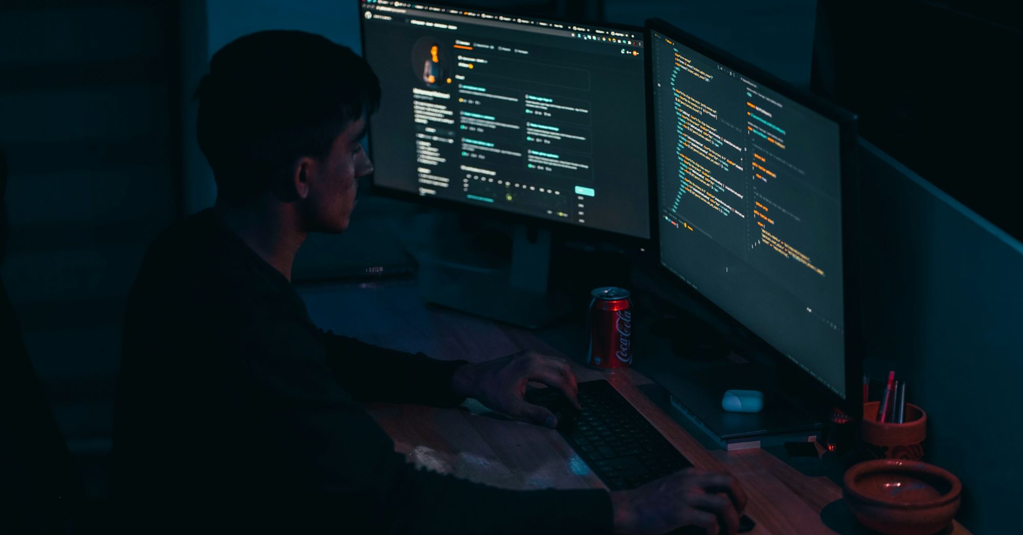 A person working at monitors in a dark office