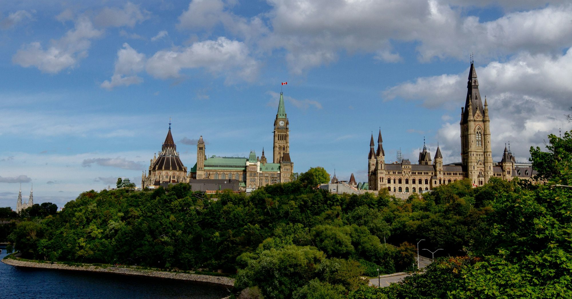 Parliament Hill in Ottawa seen across the Ottawa River under a partly cloudy sky