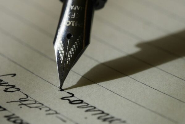 A fountain pen writing on a lined page