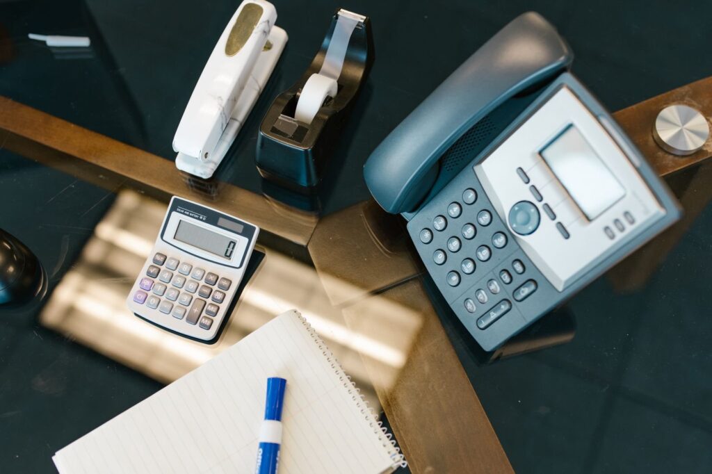 A desk phone and an open notebook on a desk, seen from above