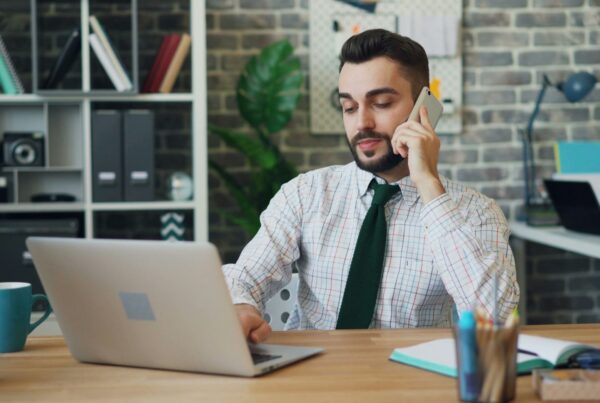 A salesperson on a phone call at his desk