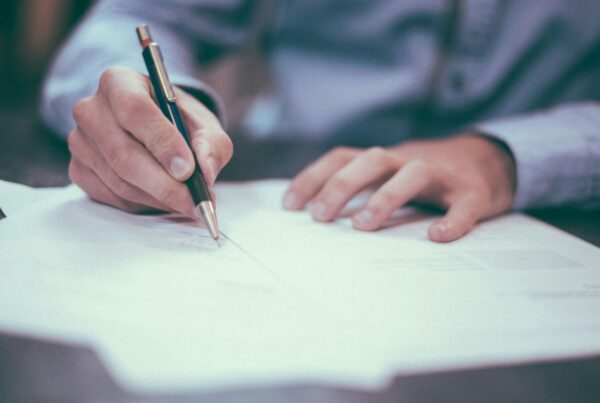 A hand signing a document at a desk