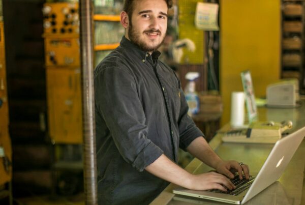 A small shop owner working on a laptop behind the counter