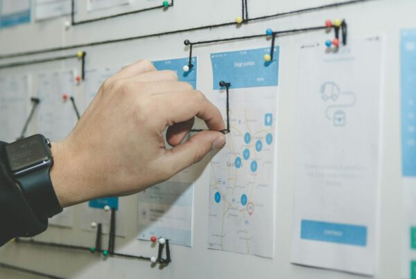 Hands arranging sticky notes and sketches on a planning wall