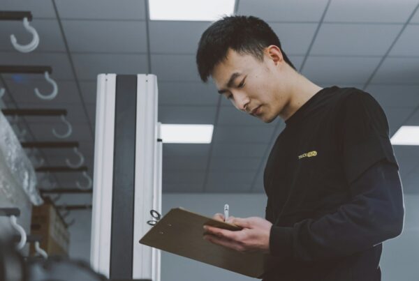 A worker holding a clipboard while checking a process in a warehouse