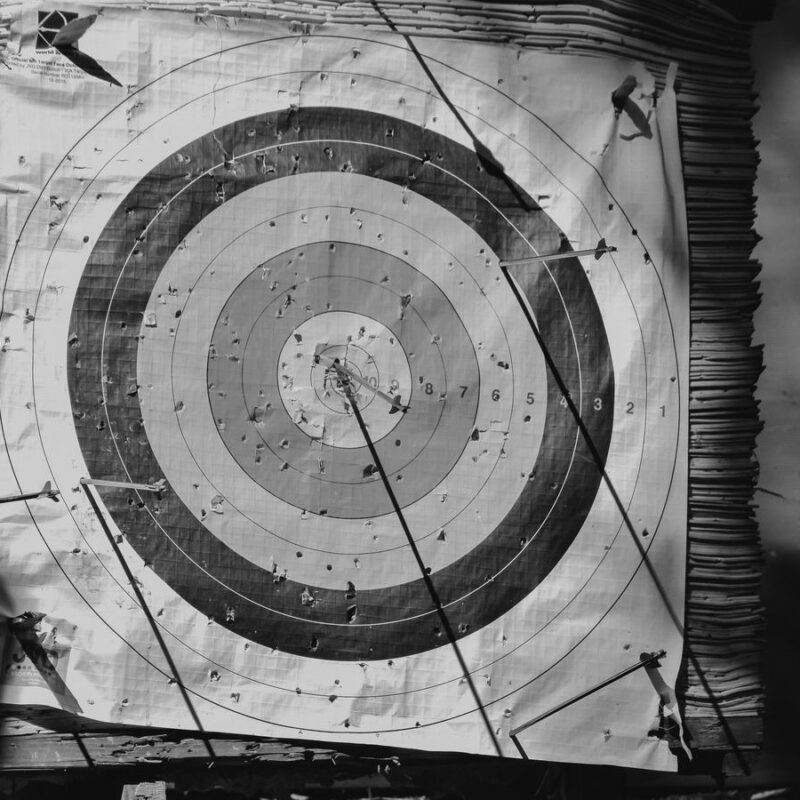 A weathered archery target with arrows landed away from the centre