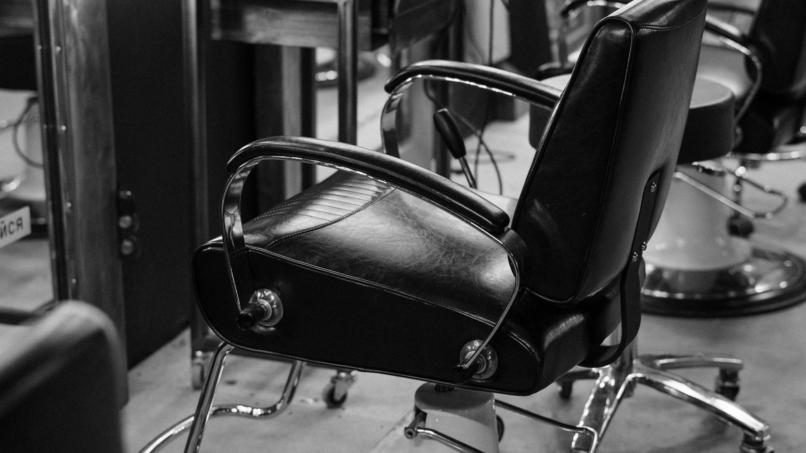 A black leather barber chair standing empty in a salon.