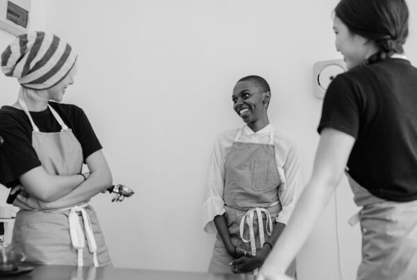 Three cafe staff in aprons talking at the counter