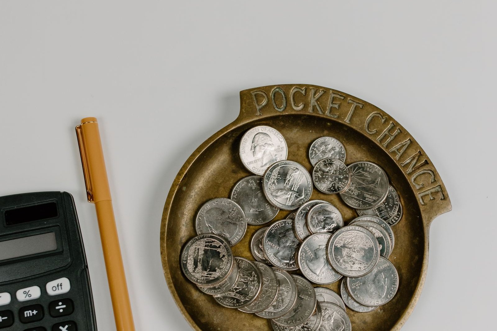 A tray of loose change beside a calculator with a blank display
