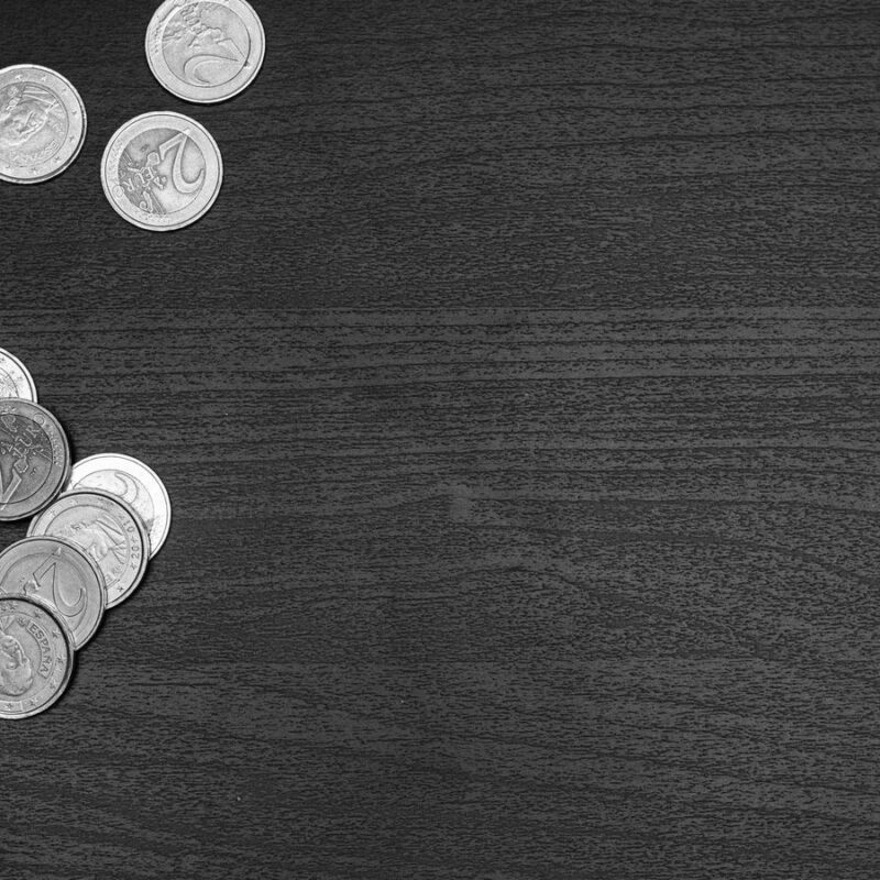 Loose coins in small piles on a dark desk