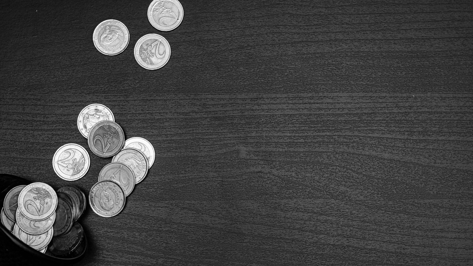 Loose coins in small piles on a dark desk