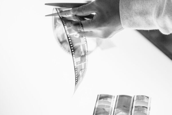 Hands cutting a strip of film with scissors over a light table