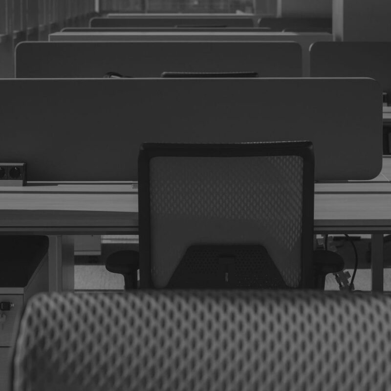 Rows of empty office desks and chairs in a vacant workspace
